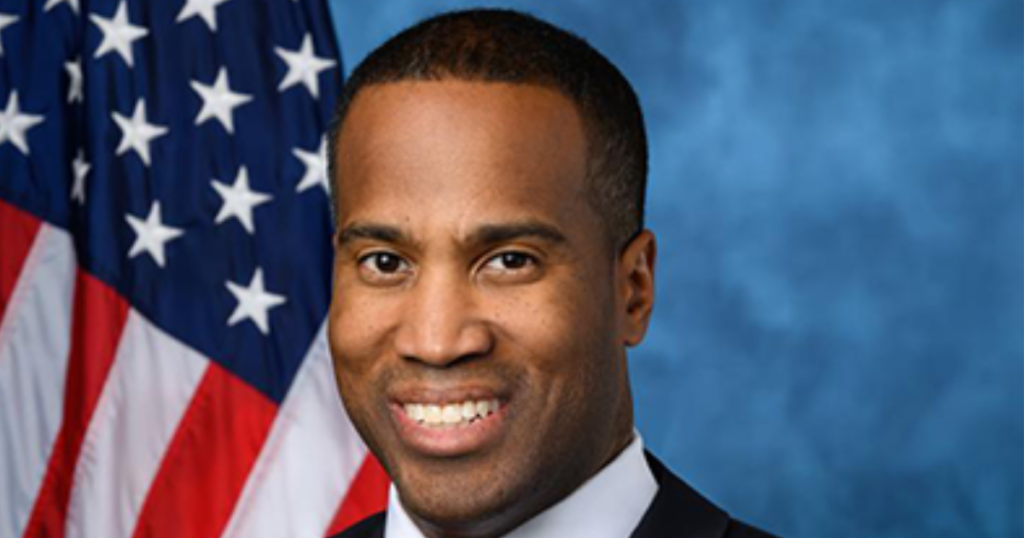 U.S. Congressman John James (MI-10) is apparently posting old photos on his social media pages to make it look like he’s in Michigan when he’s actually enjoying a tropical island vacation.